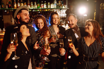 Group of happy people clinking glasses of champagne at party. Young friends celebrating winter holiday together with champagne. Party, celebration, drink, birthday concept.