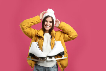 Happy woman with ice skates on pink background