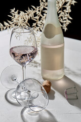 drink, alcohol and glassware concept - wine glasses and open champagne bottle dropping shadows on white surface