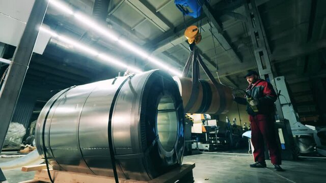 Worker transport steel coil by overhead crane at metal working factory