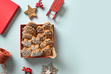 Christmas homemade glazed cookies as gift in decorative red box on blue background. View from above. Flat lay. Space for text.