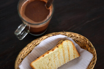 A slice of toast in a basket and a cup of warm chocolate on the table. menu for a healthy breakfast