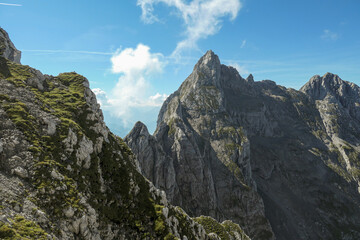 A panoramic view on Alpine slopes in Austria. There are sharp ans steep mountains and high peaks around. The Alpine slopes are almost barren, just moss overgrowing the slopes. Serenity and freedom.