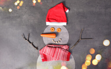 Snowman with Santa hat and scarf on grey background, flat lay. Bokeh effect