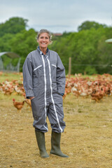 Portrait of a smiling female farmer standing in the middle of her chicken farm