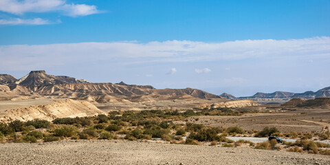 the makhtesh ramon crater from outside the south rim showing mount har katum on the lrft and the nahal nekarot stream bed winding through the negev desert with a 4x4 in the lower right