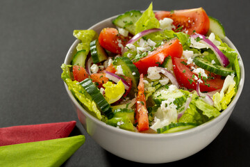 Tasty salad studio shot. This salad in closeup has lettuce, tomatoes, onion, cucumber and goat cheese.