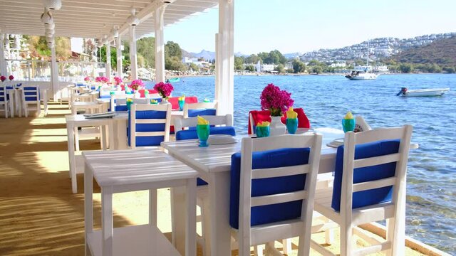 Aegean fish restaurant, tables and chairs with bougainvillea flowers next to see in Bodrum, Turkey at sunny day. It is very famous and attraction point for tourist in Bodrum.