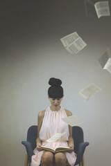 surreal moment of a woman who, while reading a book the pages float in the air