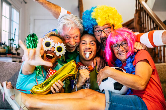 Group of crazy and happy football supporter at home enjoy the match and have fun all together - caucasian mixed ages family laugh and go craziness for a sport team and bet