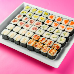 Mix of Japanese maki nori rolls in on a pink background