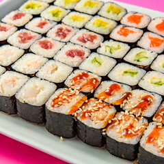 Mix of Japanese maki nori rolls in on a pink background