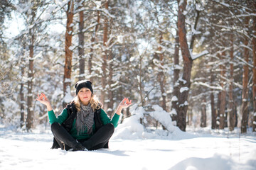Woman in winter forest in lotus pose. Adherent of doctrine of yoga in frosty weather. Tranquility and concentration concept with copy space.