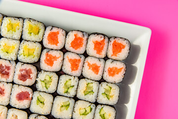 Mix of Japanese maki nori rolls in on a pink background