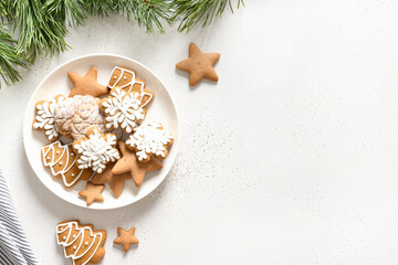 Obraz na płótnie Canvas Christmas handmade glazed cookies in plate decorated fir branches on white background. View from above. Flat lay.