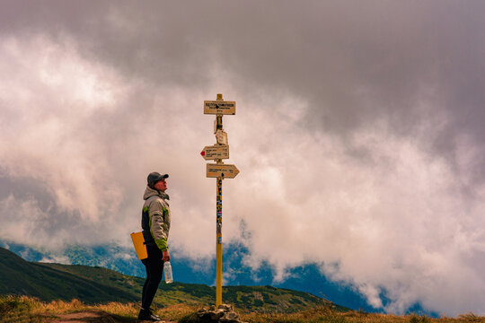 The tourist studies the indicator in the mountains, the direction to move further, the Montenegrin ridge of the Carpathian mountains.