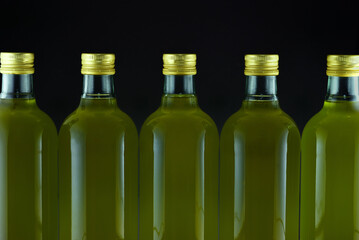 Several bottles of olive oil stand next to each other and the oil glows green
