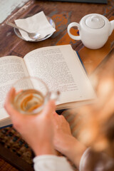 top view of an open book held by a girl drinking tea 