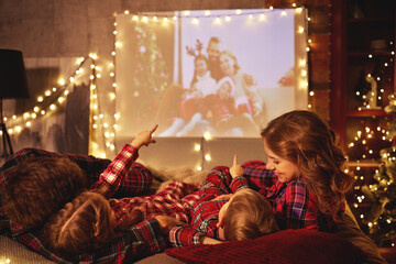 family mother father and children watching projector, film, movies with popcorn in   christmas...