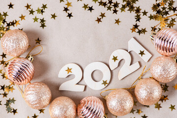 Wooden numbers 2021 on a paper background with shiny golden Christmas balls, glitter stars. Beautiful new year card