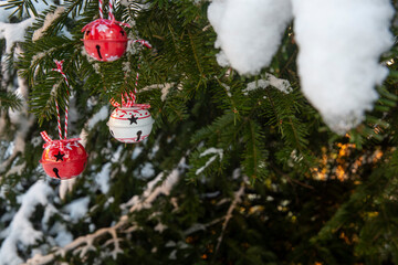 Outdoor Christmas tree with baubles, bell decoration and snow, winter background