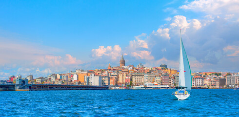 Fototapeta premium Galata Tower, Galata Bridge, Karakoy district and Golden Horn at morning with sailing Yacht - Istanbul, Turkey