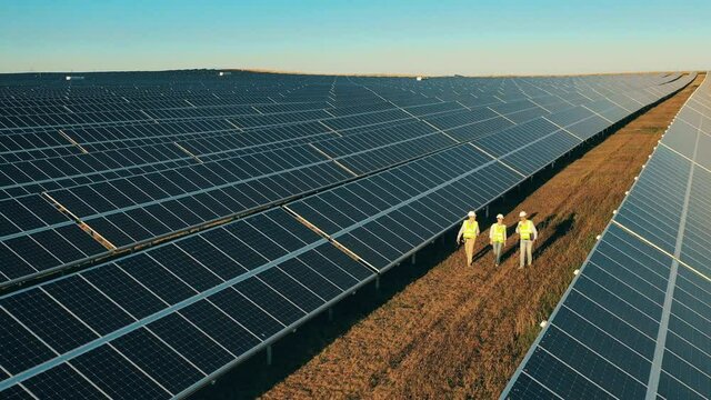 Drone shot of three solar energy specialists having a discussion at a solar power facility