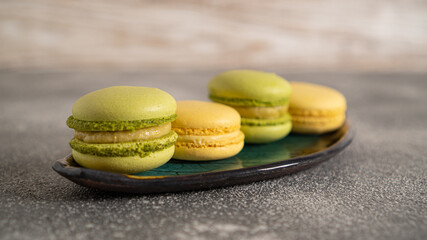 Big and small yellow macaroons on a green plate. Sweet gift for a loved one. Fresh, juicy and very sweet cakes
