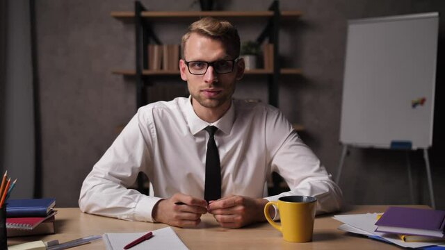 Young confident man using zoom video conference to conduct online business training at home. Professional business coach communicating with audience via webcam, e-learning during covid-19 lockdown