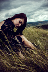 woman in a field. person relaxing in the grass. Outdoors photo of stylish girl in blue dress   Space for text. The concept of  fashion