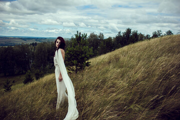 Female model posed in nature. Outdoors photo of stylish girl in white. Space for text. The concept of  fashion