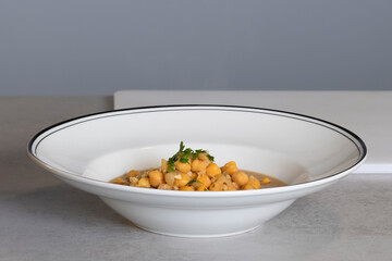 close up of a delicious looking chickpea stew with chopped parsley on a deep plate