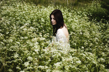 Naklejka premium Young woman with black hair and naked back among wildflowers