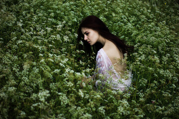 Young woman with black hair and naked back among wildflowers