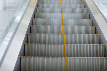 Obraz premium An escalator with a yellow line in the middle of the steps.