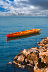 Canoe anchored by rocky water front
