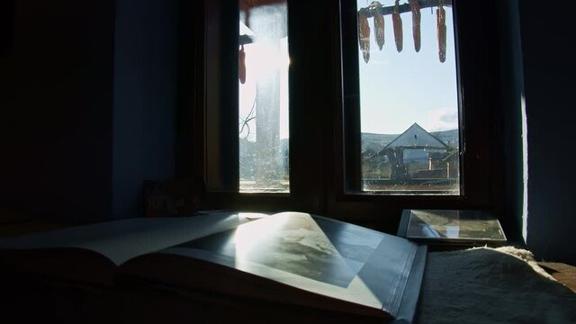 in an old house, in an old village in romania, the sun shines trhough the window on a photobook that keeps so meny memories