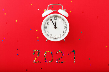 creative Alarm clock and star shaped confetti on the red background. New year or Christmas concept. top view, flat lay