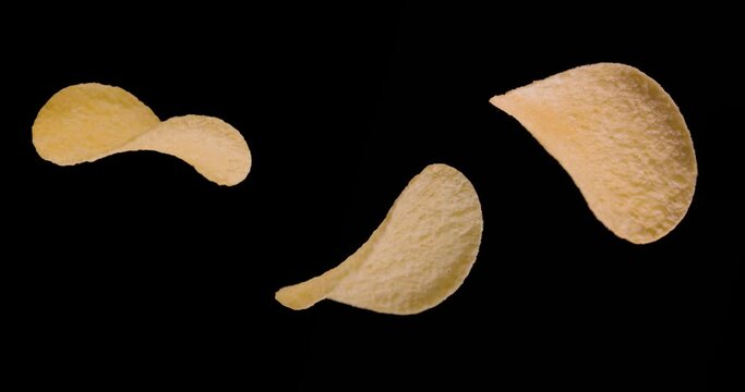Three potato chips are spinning on a black background. 