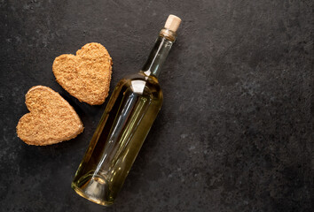 Festive dinner for two for valentine's day. Heart shaped cakes and white wine bottle on stone background with copy space for your text