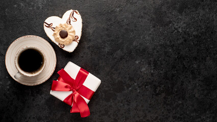 Festive breakfast for Valentine's Day. Heart shaped coffee and cake and gift with red ribbon on stone background with copy space for your text