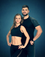 Portrait of fit athletic couple posing together on a dark blue background