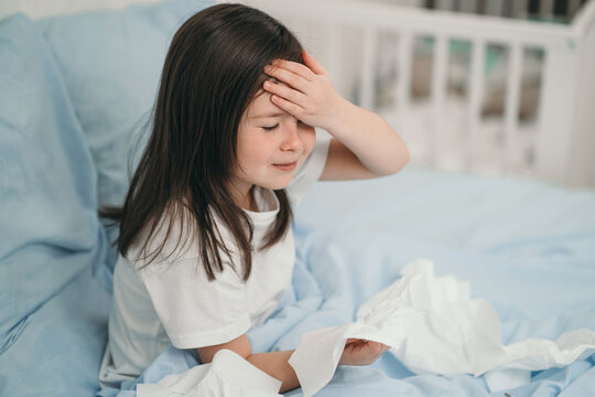 The child has a cold and is being treated at home. The girl has a headache. The child is ill and lies in bed