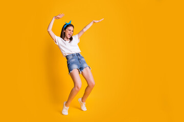 Fototapeta na wymiar Full length body size view of pretty cheerful girl having fun dancing isolated over vivid yellow color background