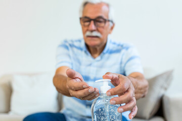 Senior disinfects hands with antibacterial gel. Hand sanitizer alcohol gel rub clean hands hygiene prevention of coronavirus virus outbreak. Old Man using bottle of antibacterial sanitiser soap.
