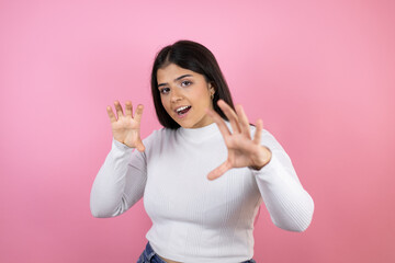 Young beautiful woman over isolated pink background smiling funny doing claw gesture as cat, aggressive and sexy expression