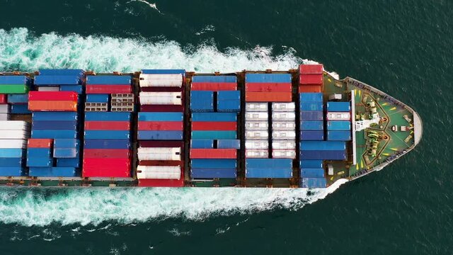 Aerial top view of cargo ship carrying container and running for export goods from cargo yard port to custom ocean concept freight shipping 4k video 