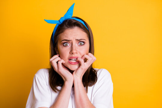 Photo of horrified girl bite gnaw fingernails wear blue headband white t-shirt isolated yellow color background