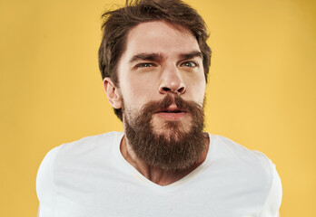 Fototapeta premium Handsome man in a white t-shirt on a yellow background emotions model stress