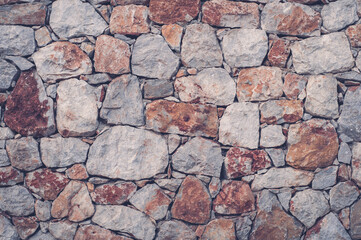 Modern wall of large unprocessed pieces of rock, stones. Background stone wall.